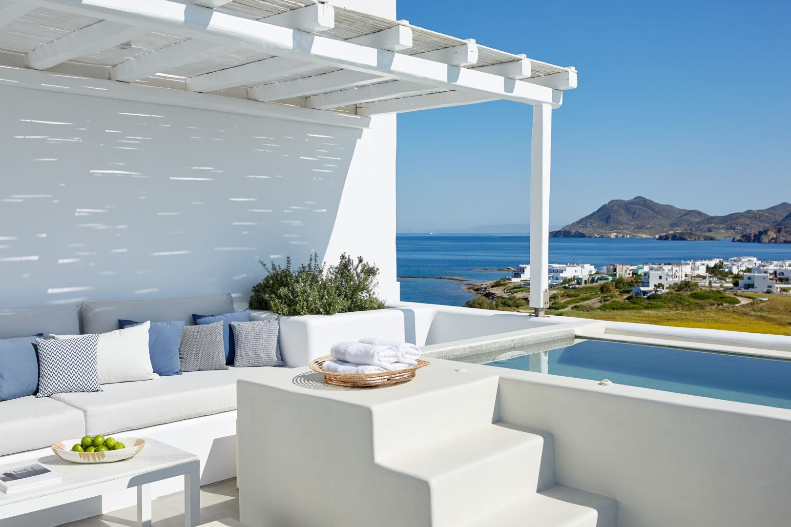 Minimalist terrace at Milos Breeze Boutique Hotel featuring a plunge pool, shaded lounge, and sweeping views of Pollonia and the Aegean Sea.
