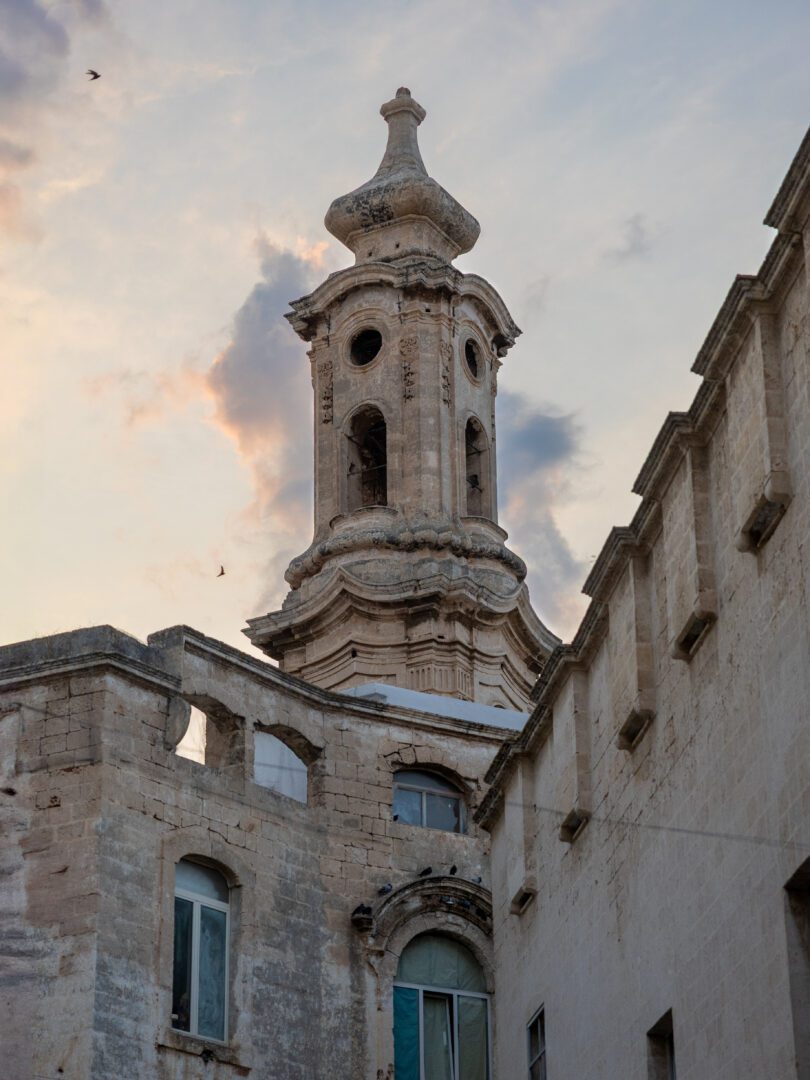 Ornate baroque bell tower in Monopoli’s old town at sunset, showcasing historic southern Italian architecture.