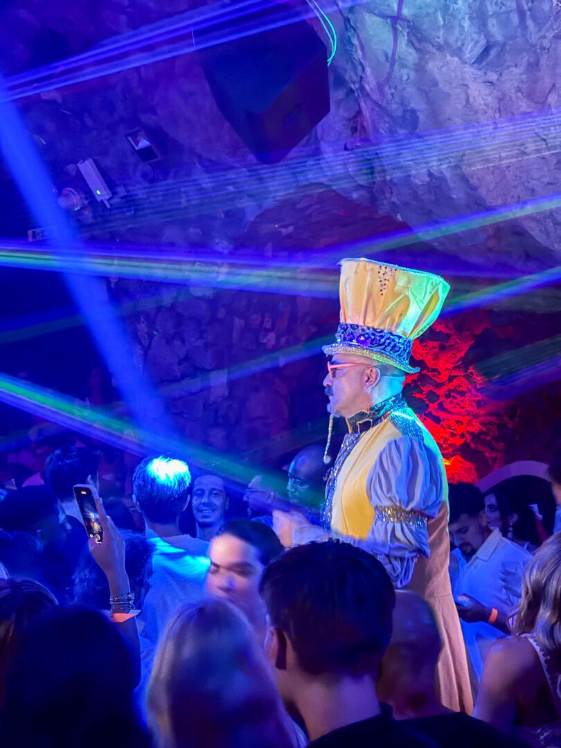Colorful lights and packed dance floor at Music on the Rocks nightclub in Positano, with a costumed emcee energizing the crowd.