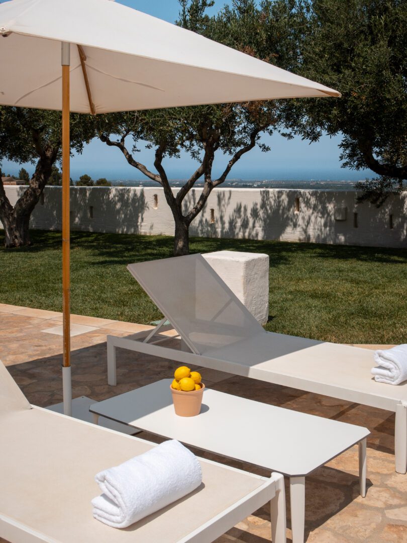 Minimalist lounge chairs and lemon decor beside the pool at Masseria Borgo Ritella in Puglia.