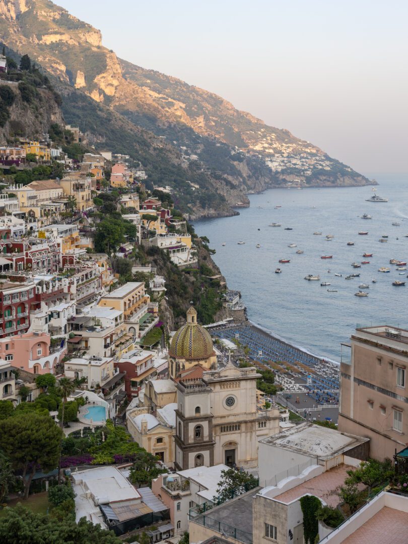 Golden hour view of Positano's colorful cliffside buildings and the Church of Santa Maria Assunta overlooking the Tyrrhenian Sea.