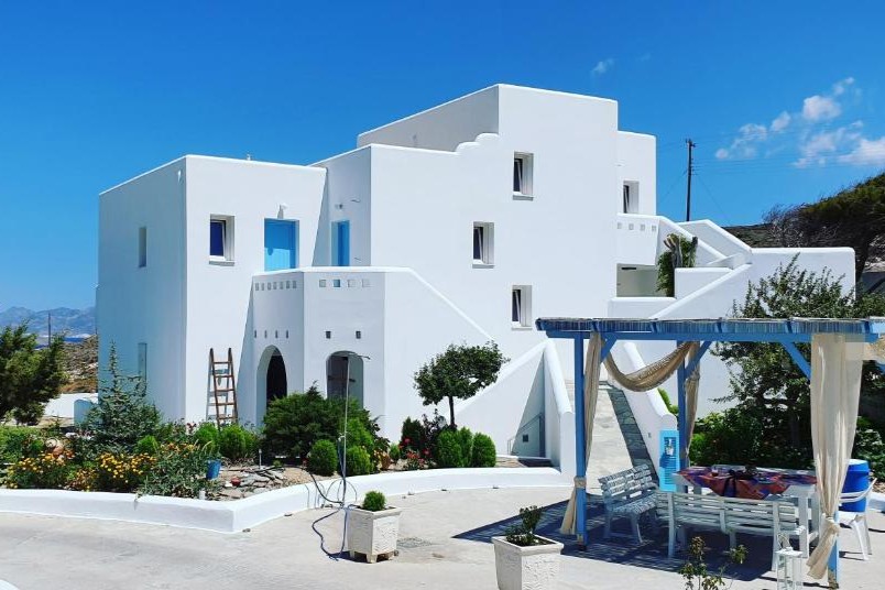 Bright and welcoming exterior of Sarakiniko Rooms Milos, surrounded by lush gardens and traditional Cycladic design elements.