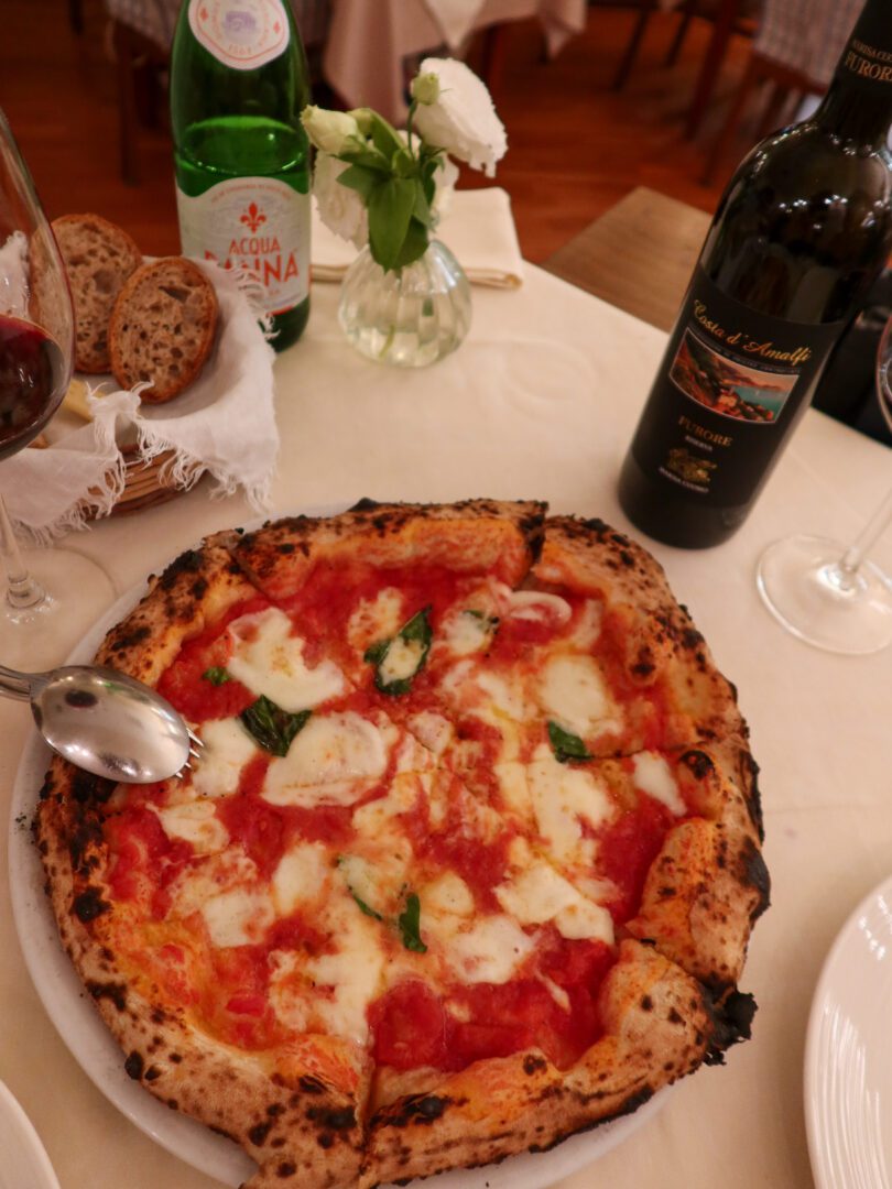 Neapolitan-style pizza with San Marzano tomatoes and fresh basil at Taverna del Leone, served with local wine and rustic bread.