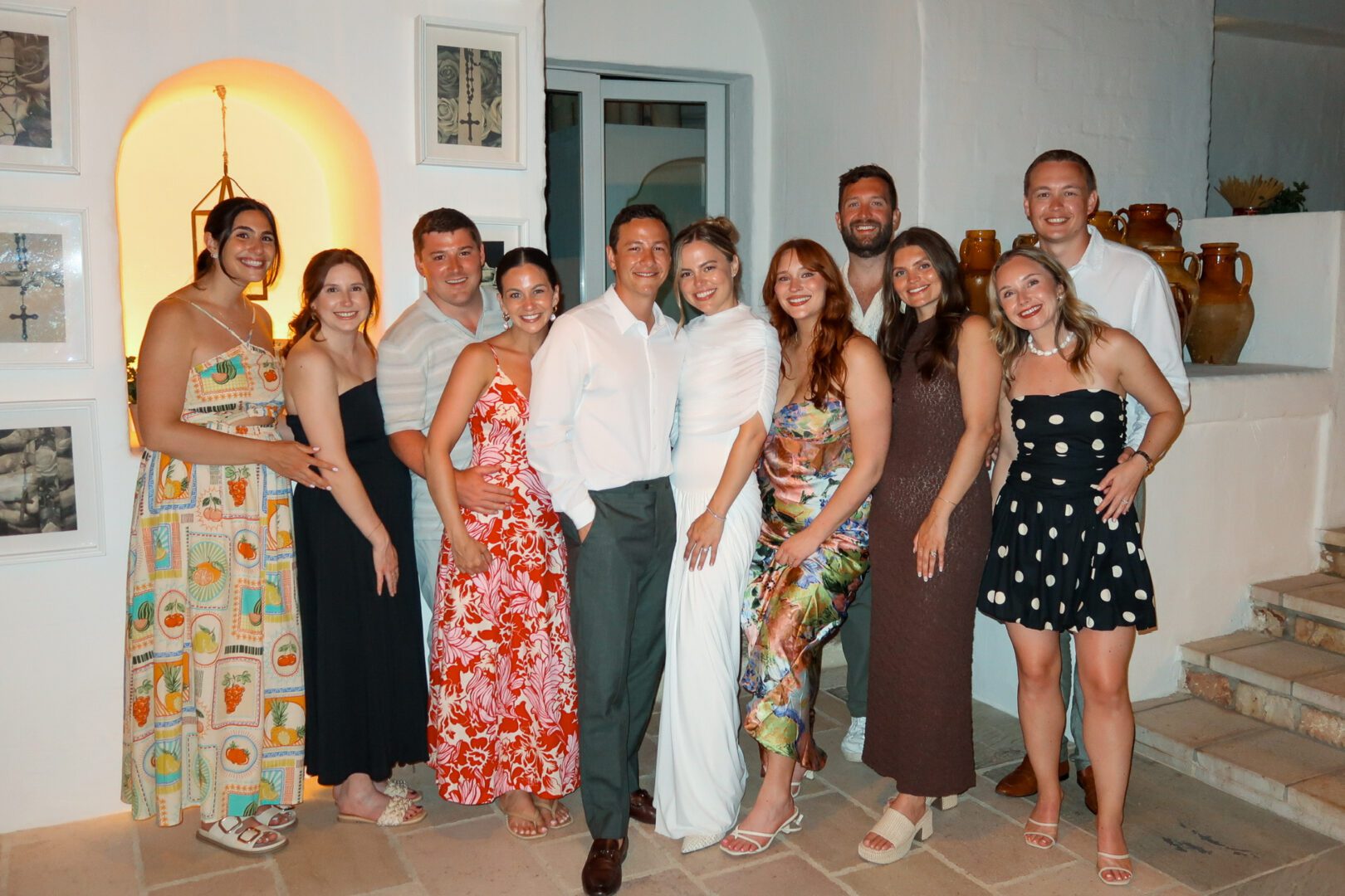 Group of friends dressed in colorful summer outfits posing at a wedding rehearsal dinner at Masseria Borgo Ritella in Puglia.
