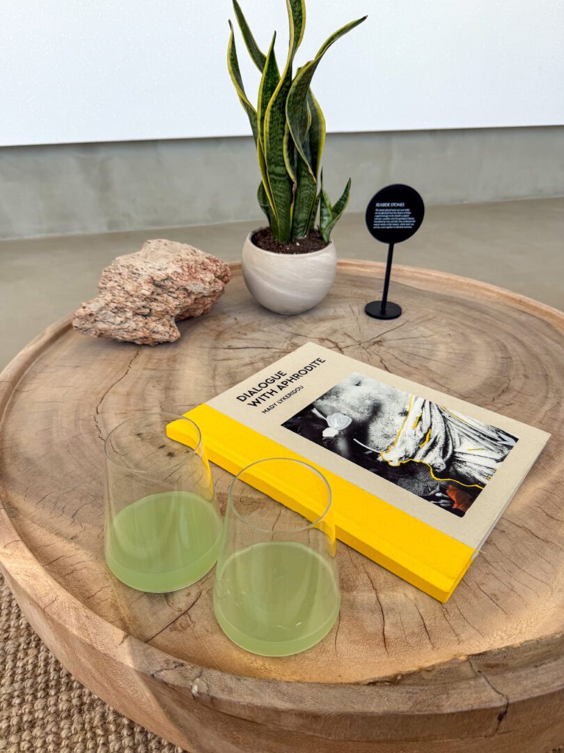 Refreshing welcome drinks served at Domes White Coast Milos reception, styled with a wooden table, modern decor, and a bright book accent.