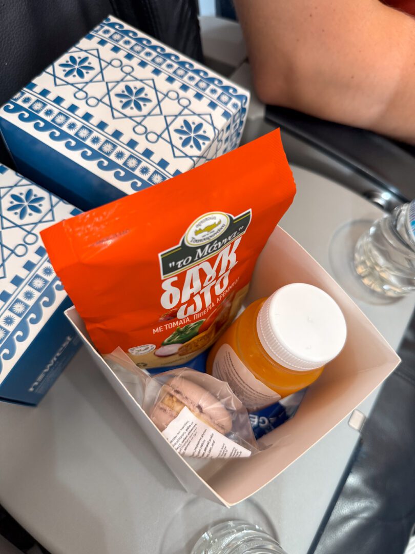 Aegean Airlines business class amenity box with snacks, juice, and treats served en route to our Santorini Greece vacation.
