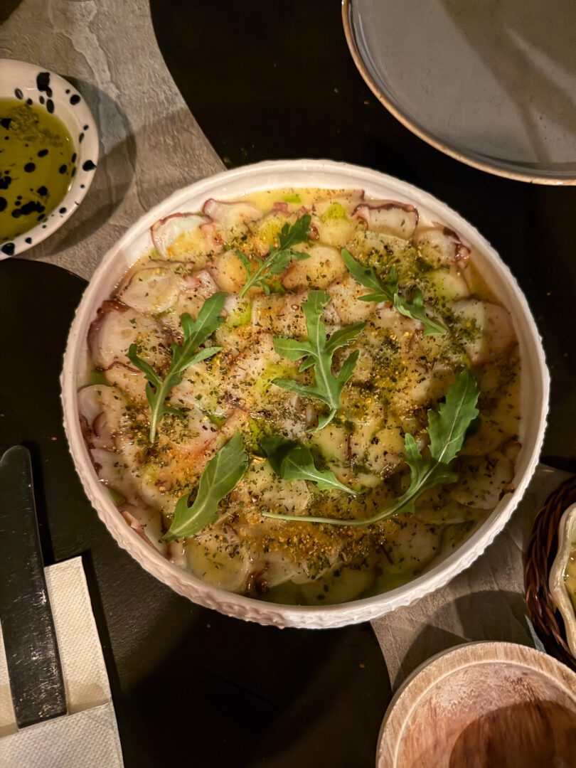 Octopus carpaccio drizzled with olive oil and herbs, served at Oenosart Restaurant in Oia, Santorini.