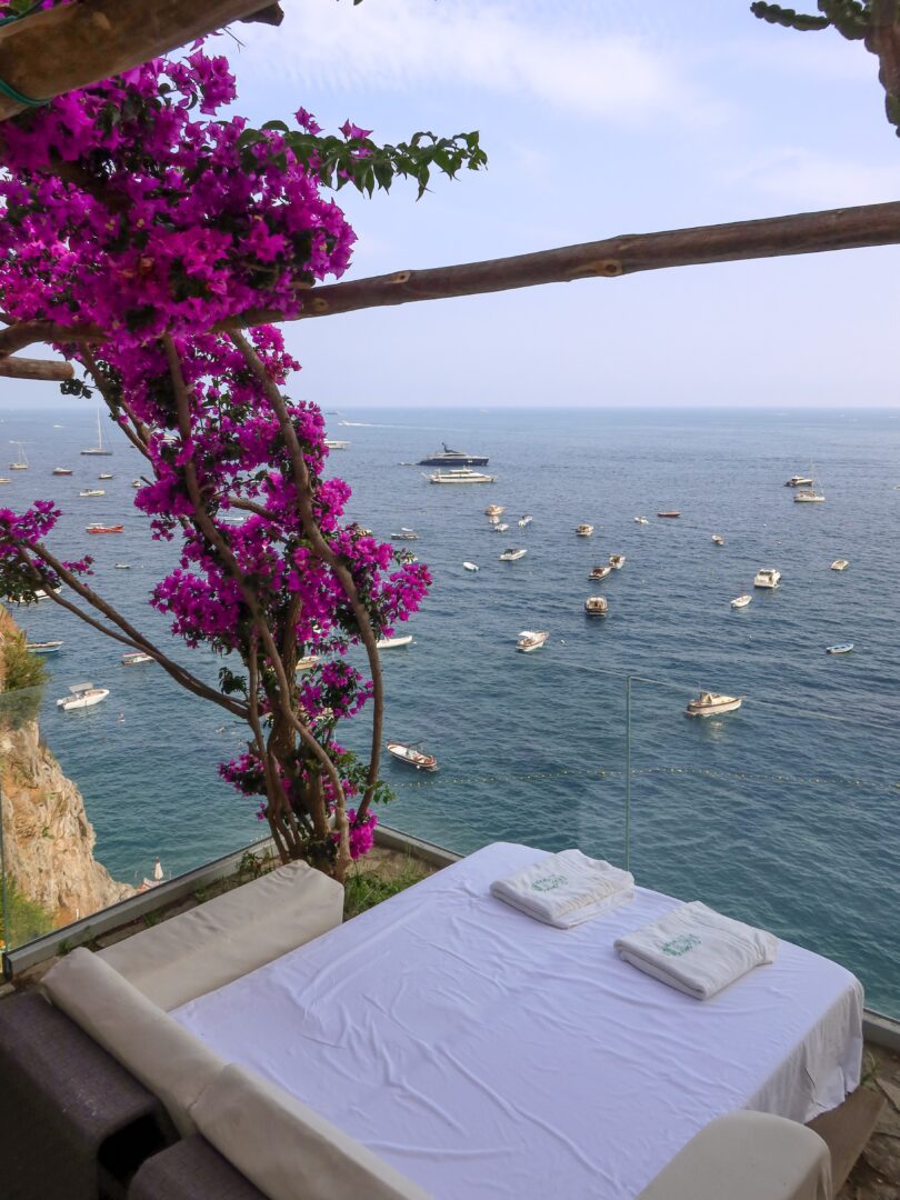 Romantic daybed at Hotel Marincanto set beneath blooming bougainvillea, perched on a cliff with panoramic views of the sea.