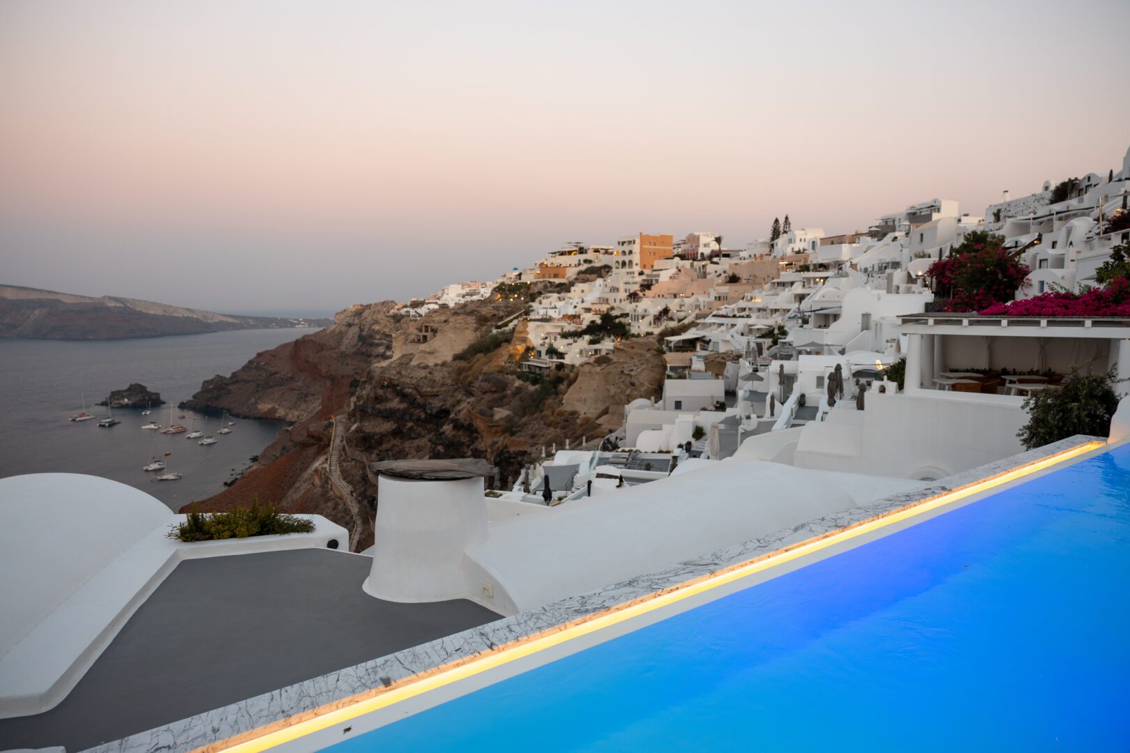 Infinity pool at Katikies Hotel Santorini overlooking Oia’s cliffside village and the Aegean Sea at sunset.