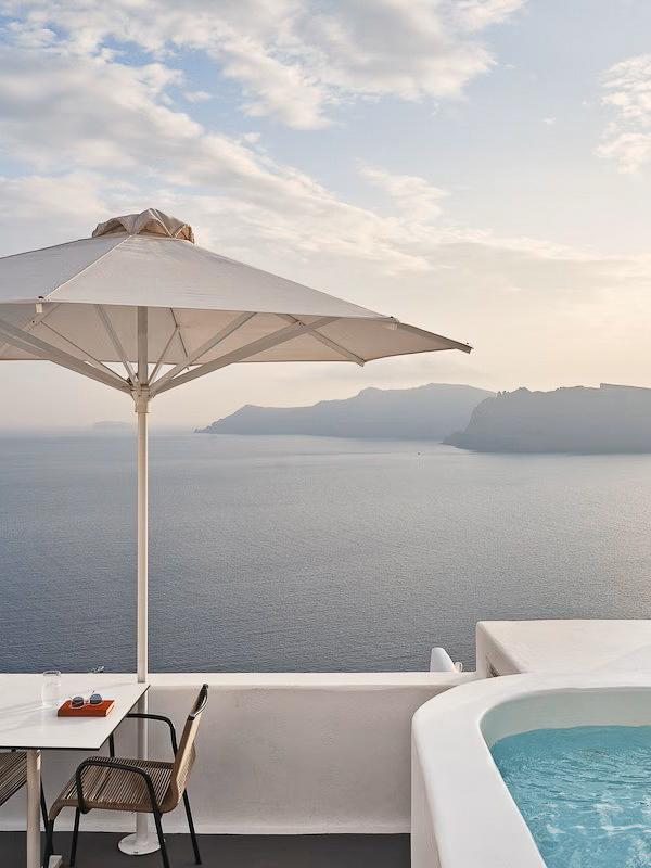 Junior Suite terrace at Katikies Hotel Santorini with private jetted tub, sun umbrella, and panoramic caldera views.